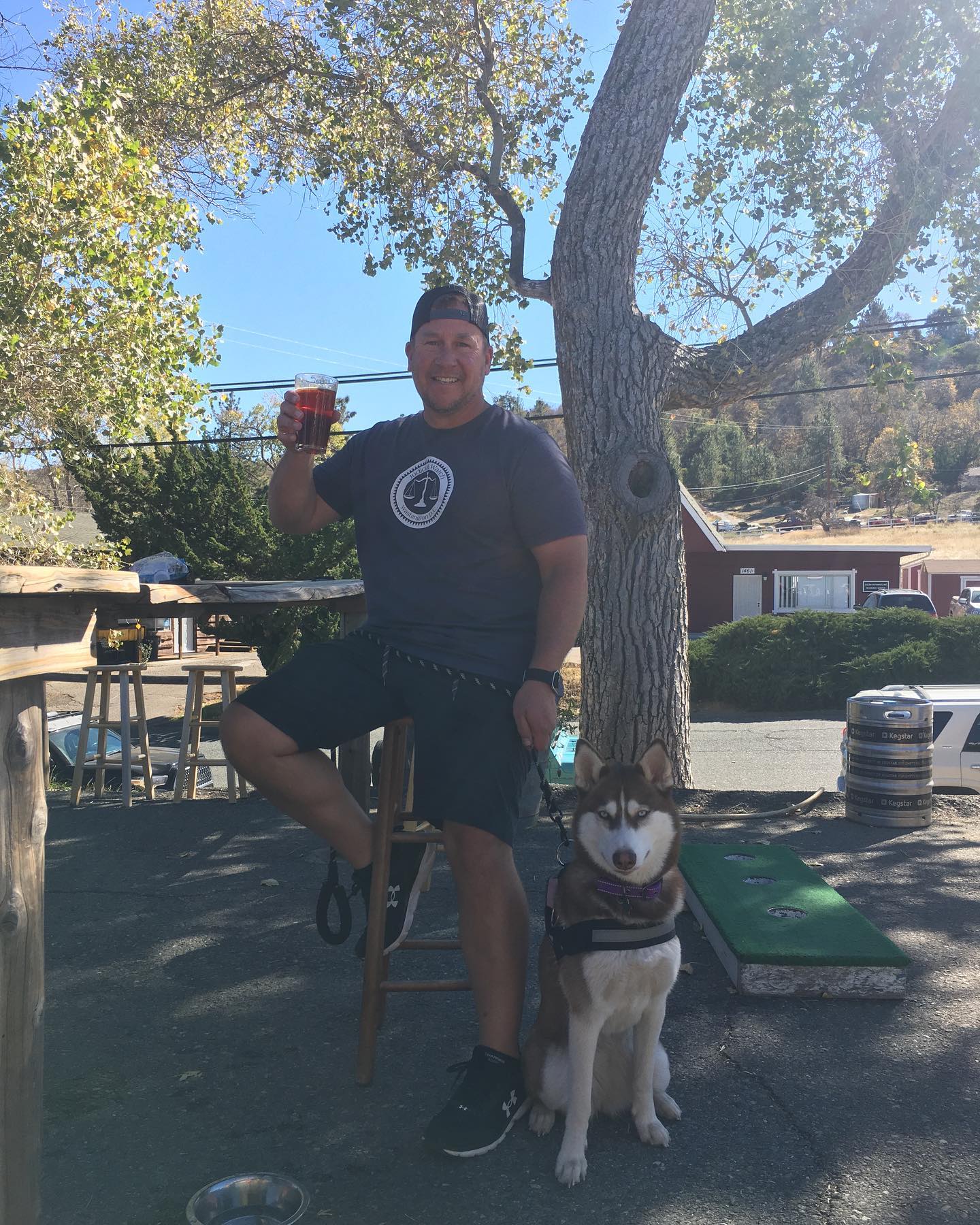 Man holding a glass of beer with his dog outside Nickel Beer Company